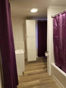 baño con cortina de ducha púrpura y suelo de madera en Unity House en Golconda
