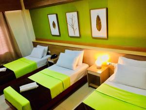 2 camas en una habitación con paredes verdes en RedDoorz Plus @ ABC Landmark Hotel, en Kidapawan