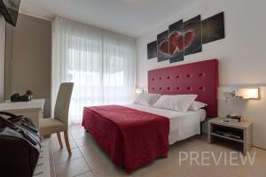 una camera con letto con testiera rossa di Hotel Picobello Pineta a Lido di Jesolo