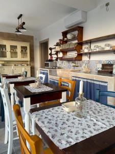 una sala da pranzo con tavoli e sedie e una cucina di Bàcula Nzícula Marzamemi a Marzamemi