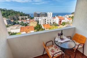 a balcony with a table and chairs and a view of the city at Apartments Pod Lozom with Seaview in Petrovac na Moru