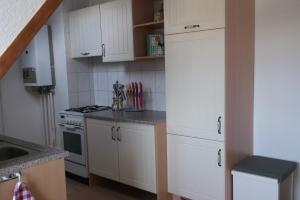a small kitchen with white cabinets and a stove at Wohnen im Holzhaus in Niesky