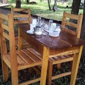 un tavolo in legno con 2 sedie e un tavolo con teiere di Nguse River Camp a Kikube