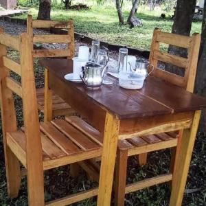 a wooden table with two chairs and a table with tea pots at Nguse River Camp in Kikube +62 photos