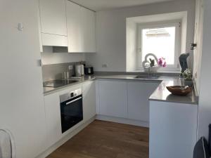 a white kitchen with white cabinets and a sink at ON the RAIL by Arcotrilogy-Homes in Arco