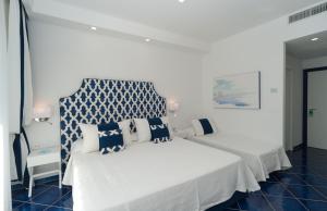 a bedroom with a white bed with blue and white pillows at Hotel Panorama in Maiori