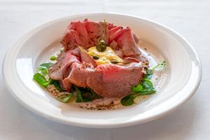 a white bowl of food with meat and vegetables at Draconerium Hotel in Dronero