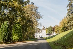 een lege weg voor een wit huis bij Barony Castle Hotel in Peebles