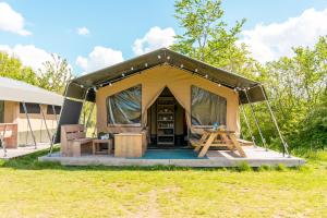 une tente avec une table et des chaises dans un champ dans l'établissement Vakantiepark de Betteld, à Zelhem