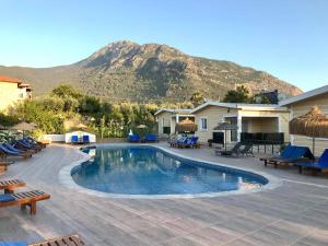 a swimming pool with chairs and a mountain in the background at Yalcin Hotel & Villas in Oludeniz