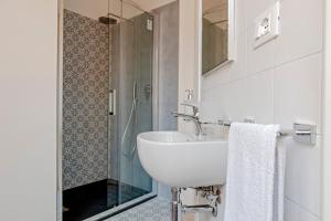 ein weißes Bad mit einem Waschbecken und einer Dusche in der Unterkunft The Boutique Apartment in Livorno
