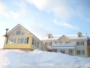 a house with a pile of snow in front of it at Pension Hoshi Ni Negaiwo in Furano