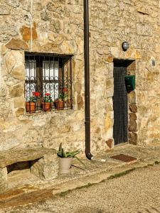 Cidones的住宿－Casa independiente y completa con una habitación "Venta de Cidones"，一座石头建筑,有两扇窗户和盆栽植物