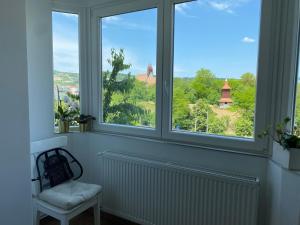 a room with three windows with a chair and a view at Rose Peony in Cluj-Napoca