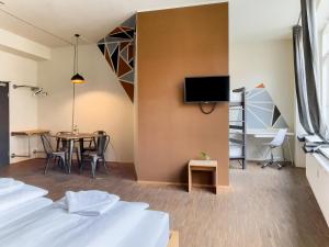 Zimmer mit einem Tisch und einem TV an der Wand in der Unterkunft Five Elements Hostel Leipzig in Leipzig