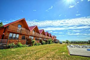 a lodge with a lawn and chairs in front of it at Domki Letniskowe Orka in Jarosławiec