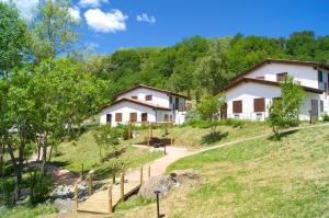 Deux maisons sur une colline avec des arbres dans l'établissement La Valle Dei Caprioli Village Bungalow Park - Freelandia Azienda Agricola, à Montescudo