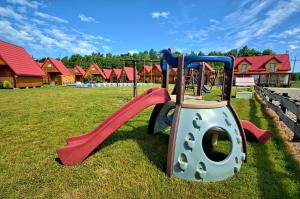 a playground with a slide in the grass at Domki Letniskowe Orka in Jarosławiec