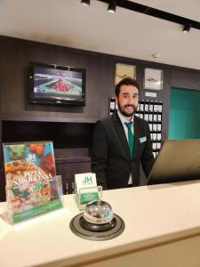 a man in a suit standing next to a counter at Just Hotel Lomazzo Fiera in Lomazzo