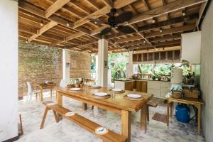 a dining room with a wooden table and a kitchen at Higala Hostel Siargao in General Luna