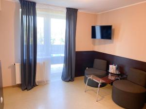 a living room with a chair and a tv at Ośrodek Wypoczynkowo-Rehabilitacyjny Perła Borów in Tleń