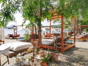 a group of beds on a beach with a tree at Summer Feel suites in Poros