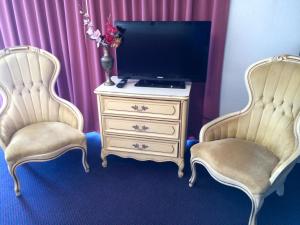 2 sillas sentadas junto a una cómoda con TV en Crystal Palace Inn Brownfield, en Brownfield