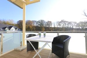 a white table and chairs on a deck with a view at Haus Sterntaucher Whg 05 mit Balkon in Thiessow