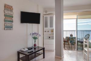 uma sala de estar com uma mesa e uma televisão na parede em Apartamento Sarai em Icod de los Vinos