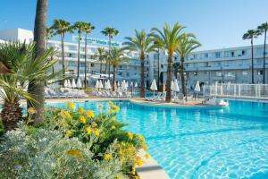 uma piscina com palmeiras e um hotel em Protur Vista Badia em Sa Coma