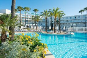 a swimming pool with palm trees and a hotel at Protur Vista Badia in Sa Coma