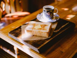 a plate with a piece of bread and a cup of coffee at Guesthouse Hitoyado in Shizuoka