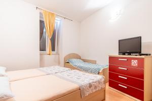 a bedroom with two beds and a tv on a dresser at Apartment Goge in Split