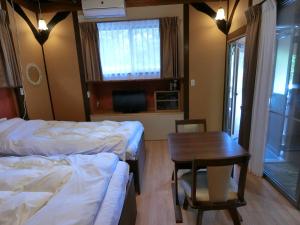 a room with two beds and a table and a chair at Shirahama Meiji Villa in Shirahama