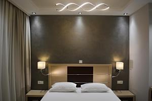een hotelkamer met een groot bed met twee witte kussens bij Phaethon Apartments & Studios in Kallithea