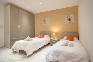 1 dormitorio con 2 camas con sábanas blancas y almohadas de color naranja en Modern Beach APT w Fantastic Sea Views - 1, en Mellieħa