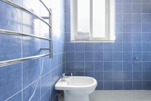 a blue tiled bathroom with a toilet and a window at Ta Gianni Guest House in Sliema