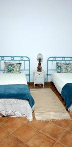 ein Schlafzimmer mit 2 Betten und einem Tisch mit einer Lampe in der Unterkunft Casa do Avô Tó in Reguengos de Monsaraz