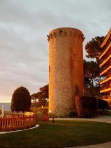 a tall brick tower sitting next to a fence at Pensió Costa Brava in Sant Antoni de Calonge