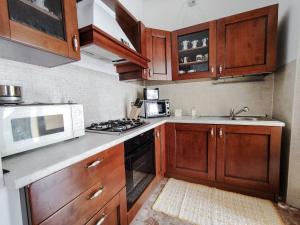 una cucina con armadi in legno, piano cottura e forno a microonde di Appartamento Funtanedda - Affitti Brevi Italia a Triei