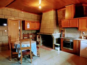 une cuisine avec des placards en bois, une table et une cheminée dans l'établissement Casa do Meia Noite, à Gralhas