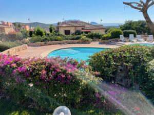 a swimming pool with purple flowers and a house at Fiordaliso Aurora in Olbia
