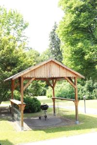 a wooden pavilion with a grill in a park at VITA Ferienresidenz in Neu Kaliß