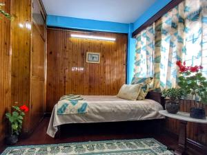 um quarto com uma cama num quarto com paredes de madeira em West Point Backpackers Hostel em Darjeeling