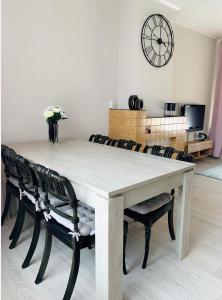 mesa de comedor con sillas y reloj en la pared en Cosy house in the heart of the center! en Oostburg