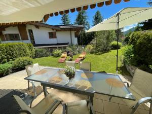 a patio with a glass table and chairs and an umbrella at Haus Elisengrund am Geigenbuehel - chalet privé in Seefeld in Tirol +78 photos