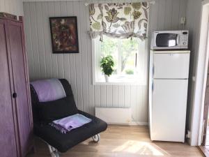 a kitchen with a chair and a refrigerator and a window at Stråvalla Hulegården in Stråvalla