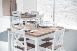 mesa de comedor blanca con sillas blancas y mesa de madera en Masseria Donna Nina en Ostuni