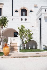 a white building with two vases in front of it at Masseria Donna Nina in Ostuni