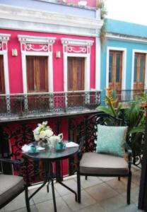 - un balcon avec une table et des chaises en face d'un bâtiment dans l'établissement Fortaleza Suites Old San Juan, à San Juan